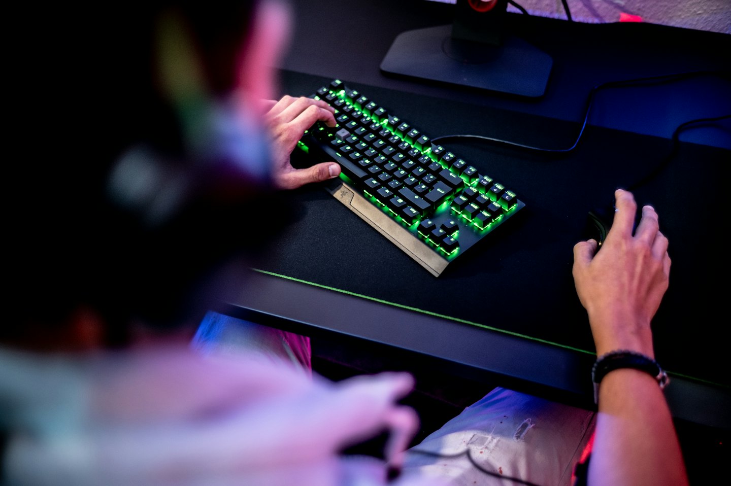 Jogador usando teclado mecânico e mouse com iluminação verde.
