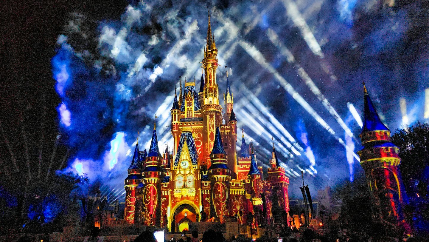 Castelo iluminado por padrões coloridos à noite.