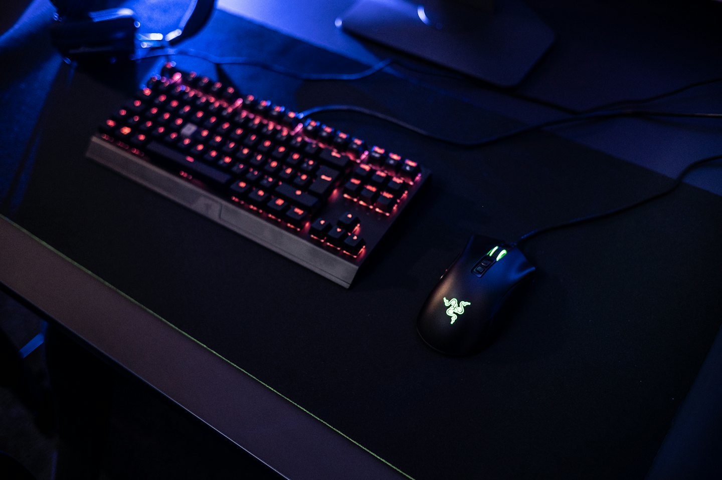 Teclado e mouse de jogo iluminados sobre a mesa.